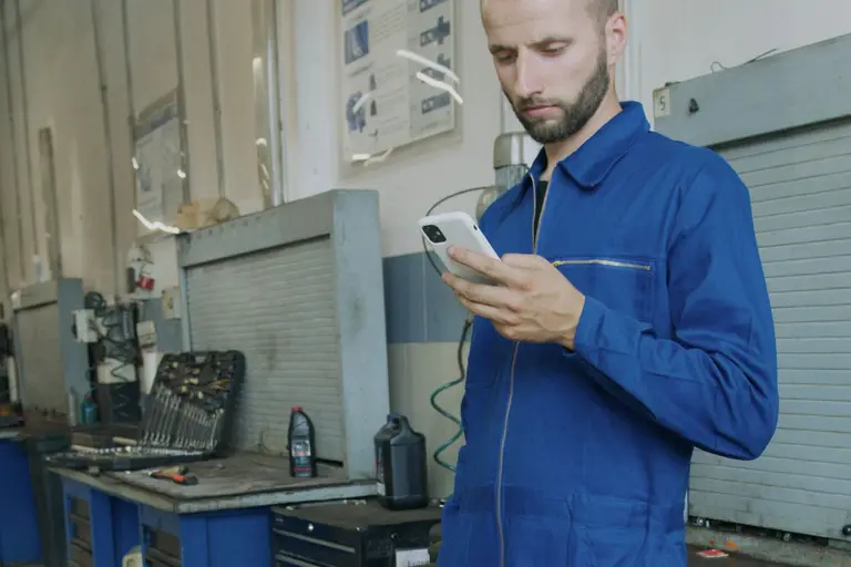 An engineer reading a text message on his phone.