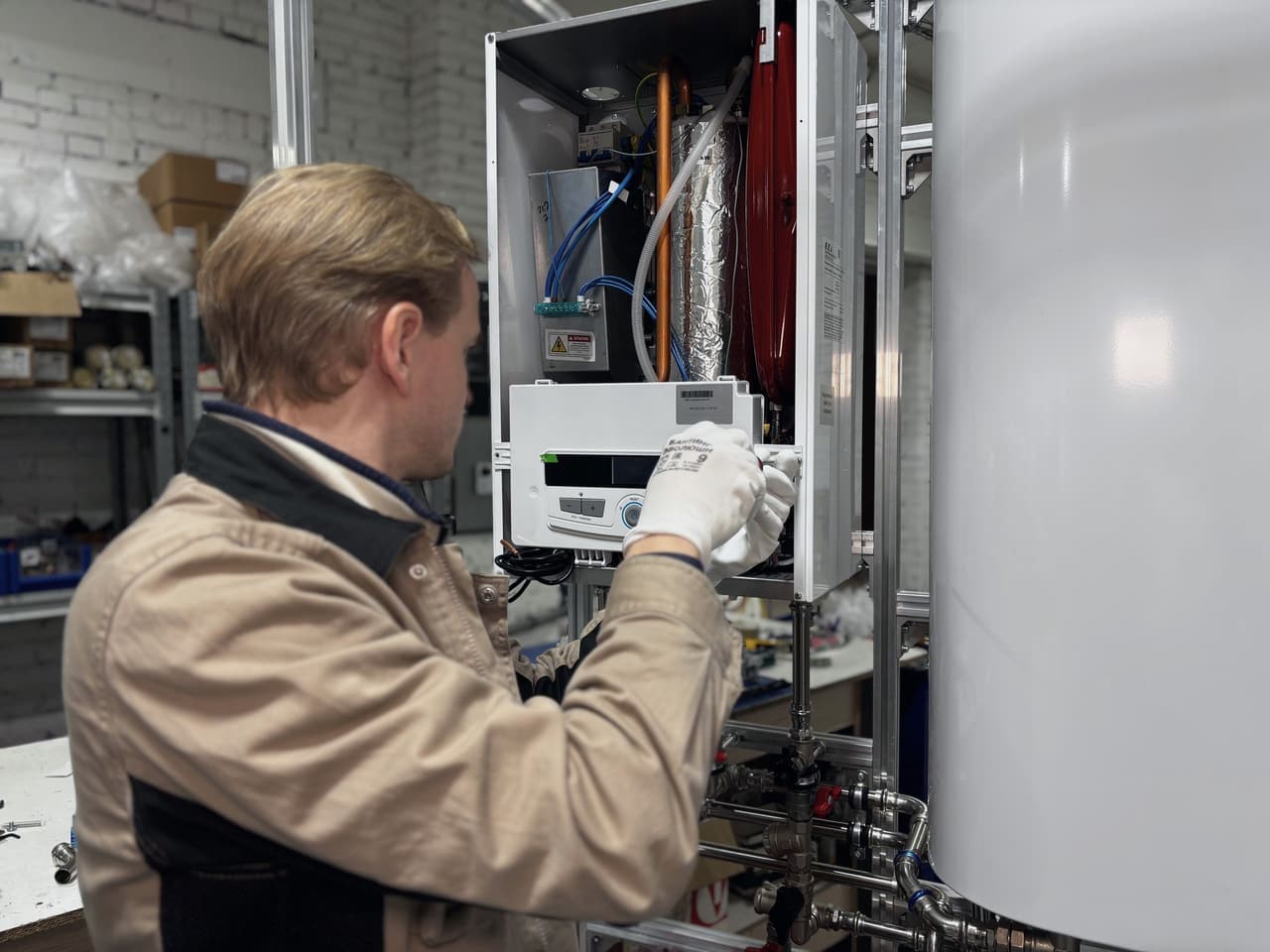 A heating engineer working inside an open wall-hung boiler unit.